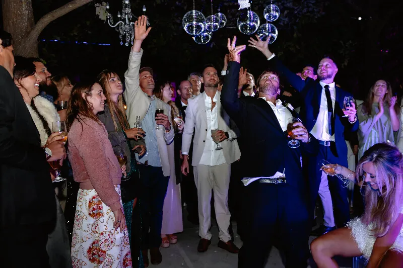 A groom and his friends with their hands in the air on the wedding dance floor