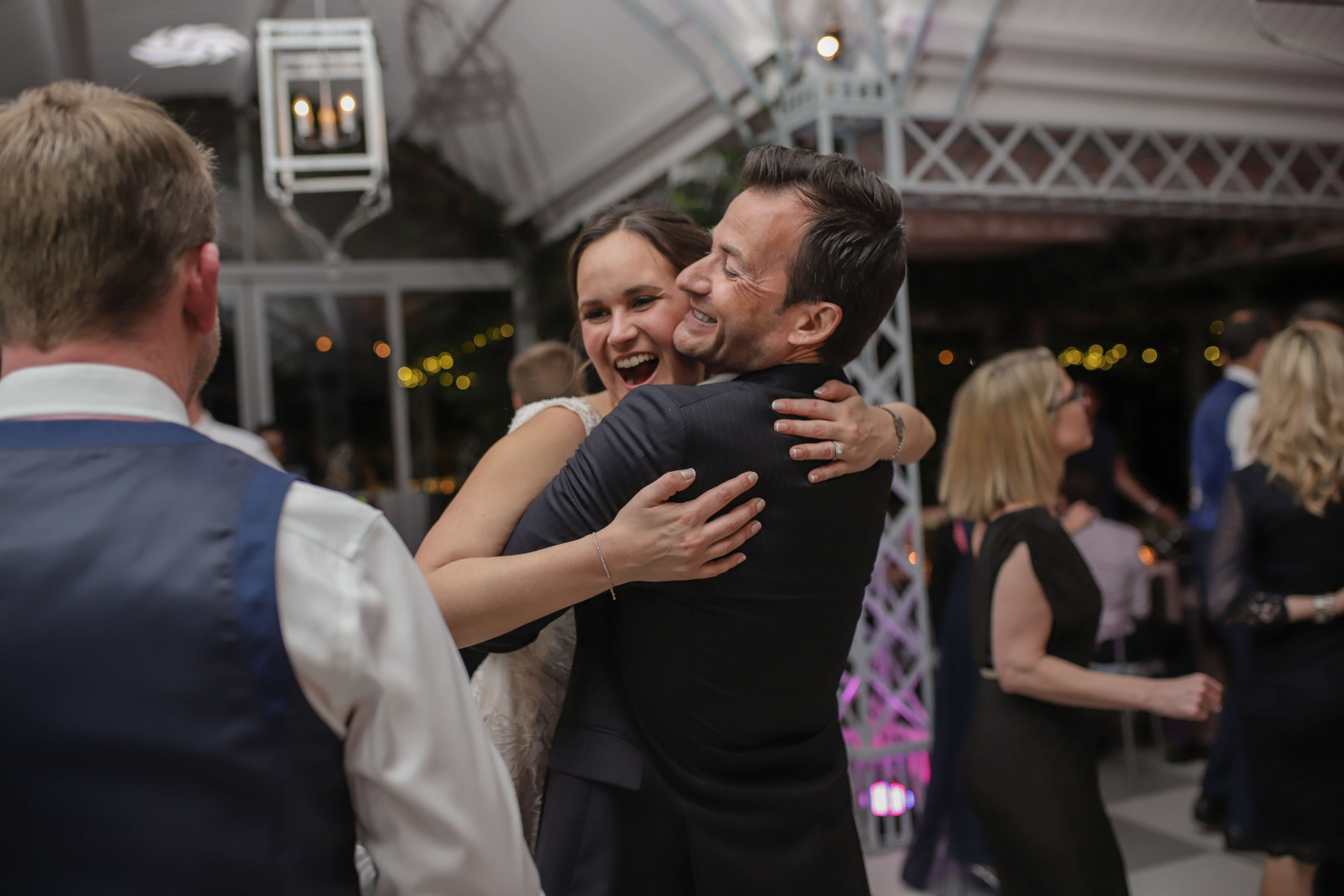 A bride ecstatic that she is having the best night of her life while hugging her friend on a dance floor.