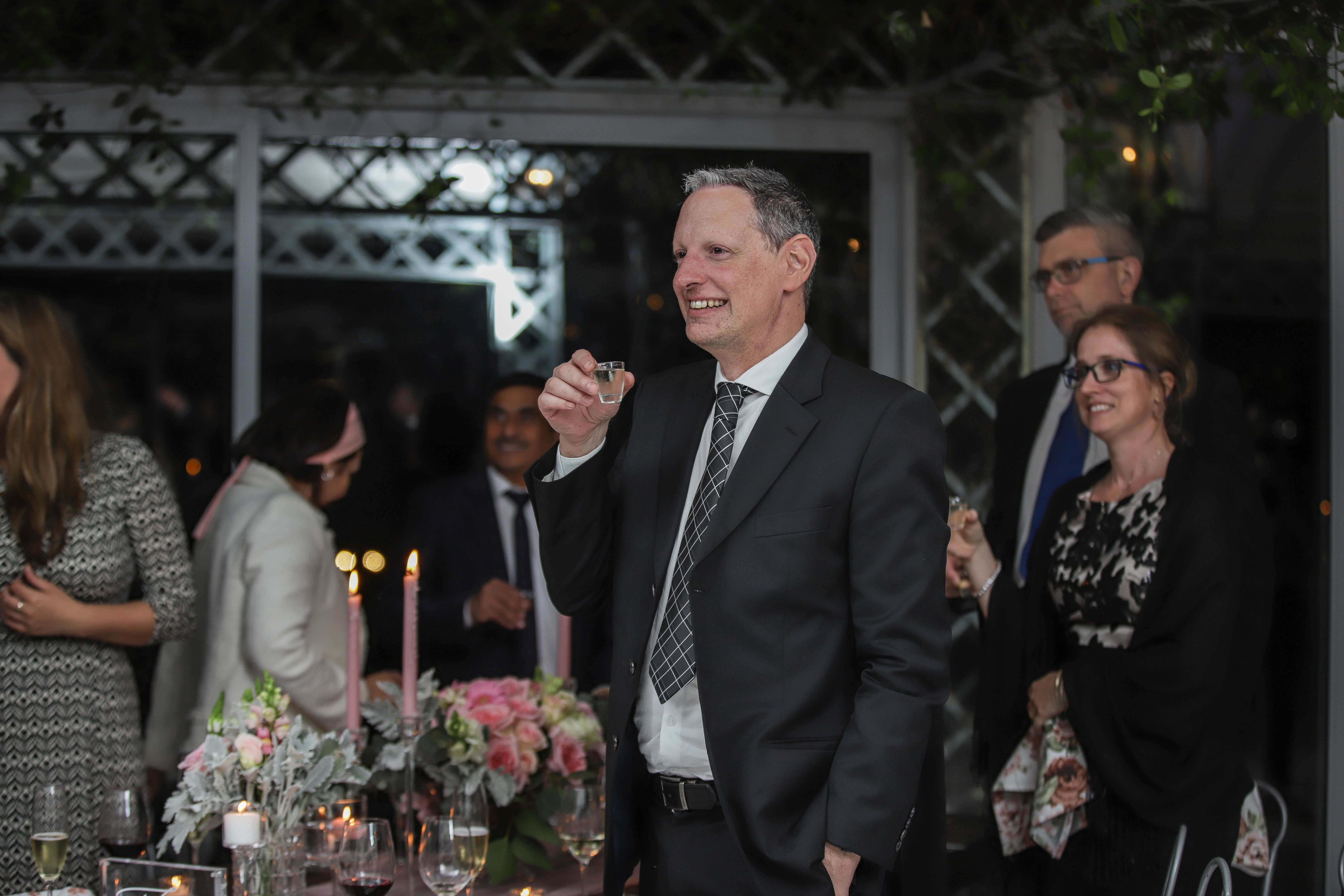 A man with a full shot glass about to give a toast to a wedding speech.