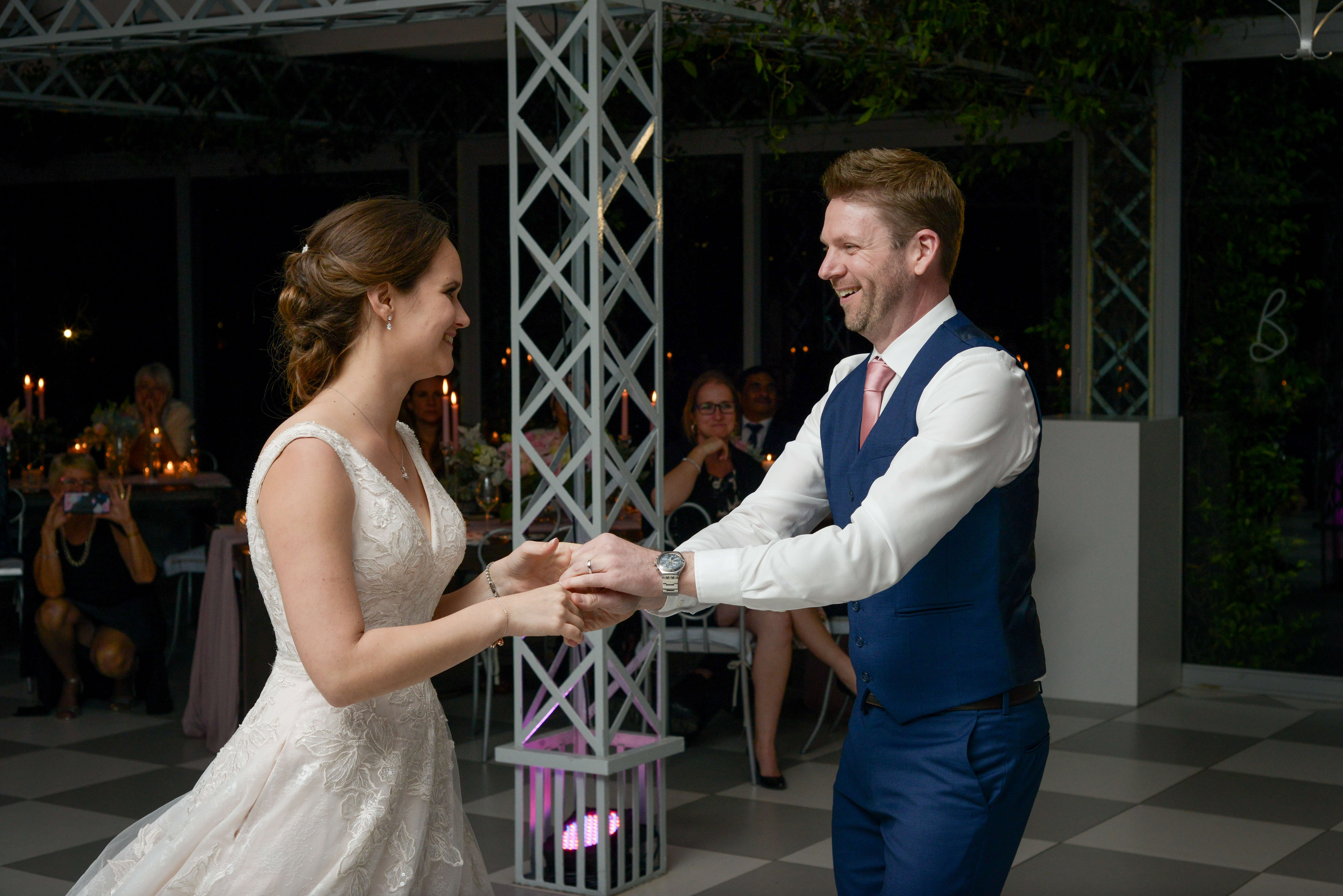 Bride and groom hand in hand for their first dance.