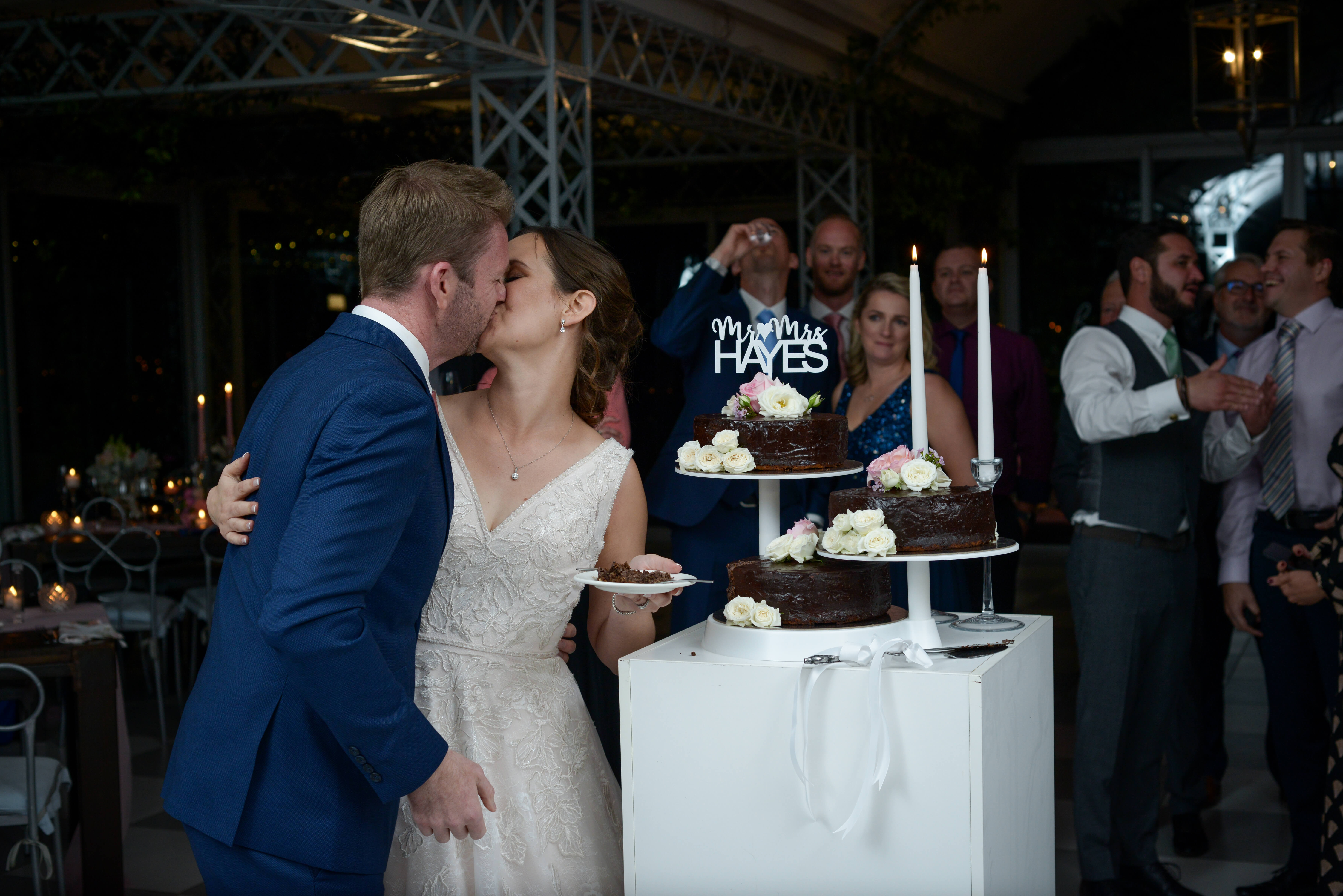 Groom and his bride kissing after cutting their wedding cake.