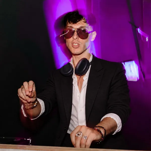 Liam, founder of The DJ Company, at the decks under purple lights