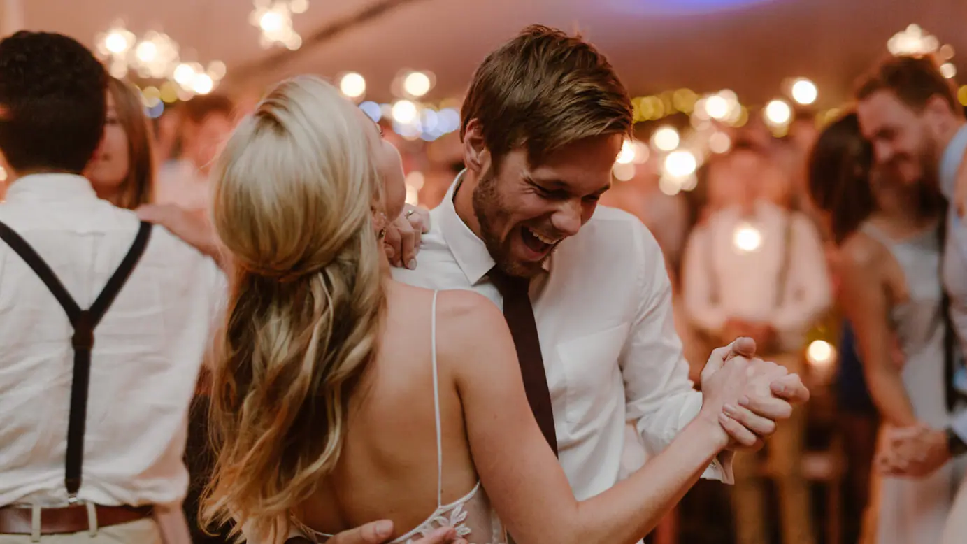 Ramsay laughing as he dances close with Sarah under glowing festoon bulbs in the marquee at their Constantia wedding