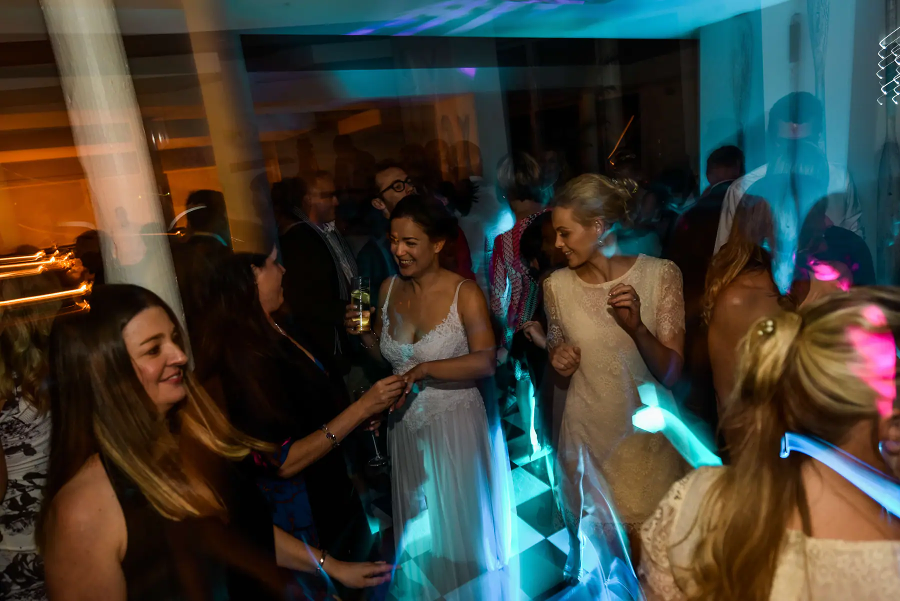 Karen with a drink laughing with friends on the chequered dance floor in teal and pink light