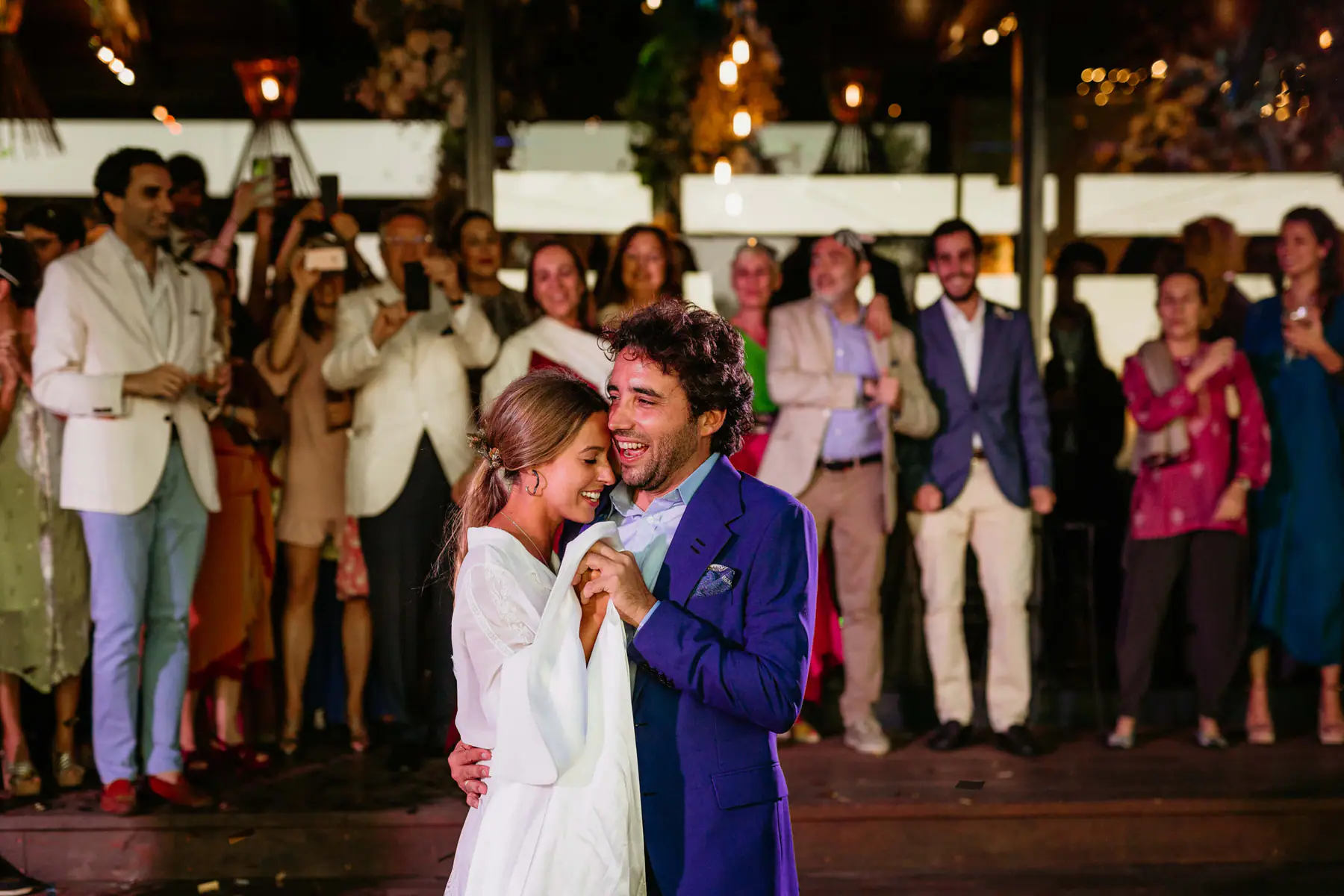 Barbara and Mario laugh cheek to cheek in their first dance while guests film on their phones