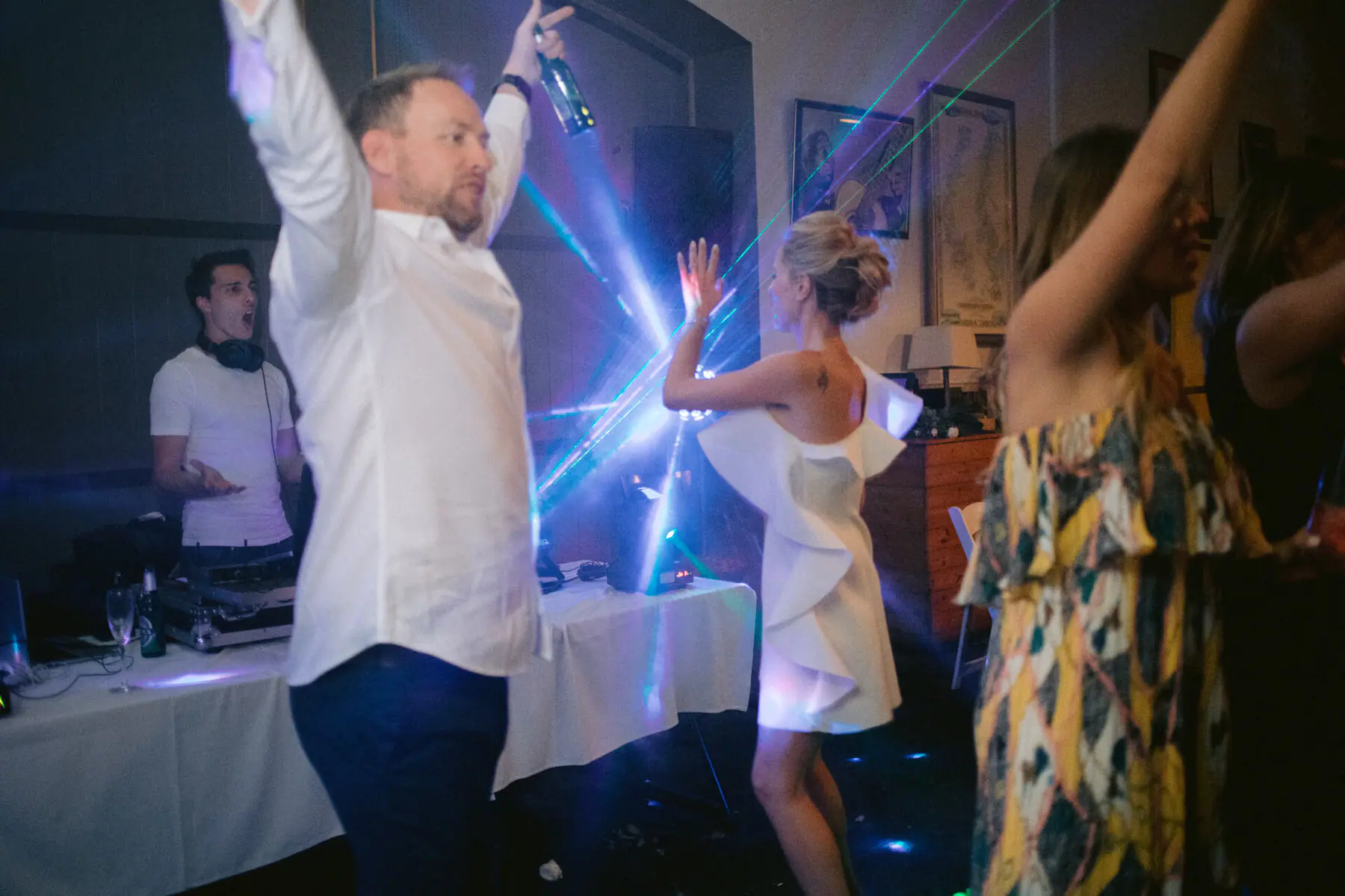 Greg raises a beer as Kirsten dances into the laser beams and The DJ Company's DJ calls out from the booth
