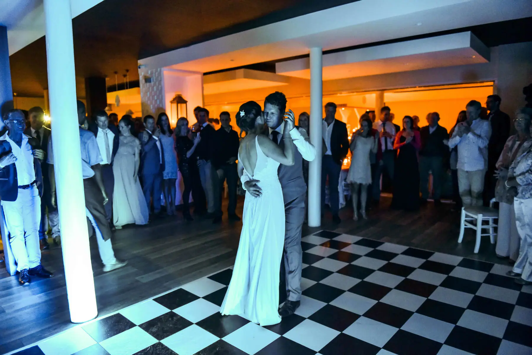 Karen and Lial's first dance on a black and white chequered floor in Plettenberg Bay, guests watching in blue light