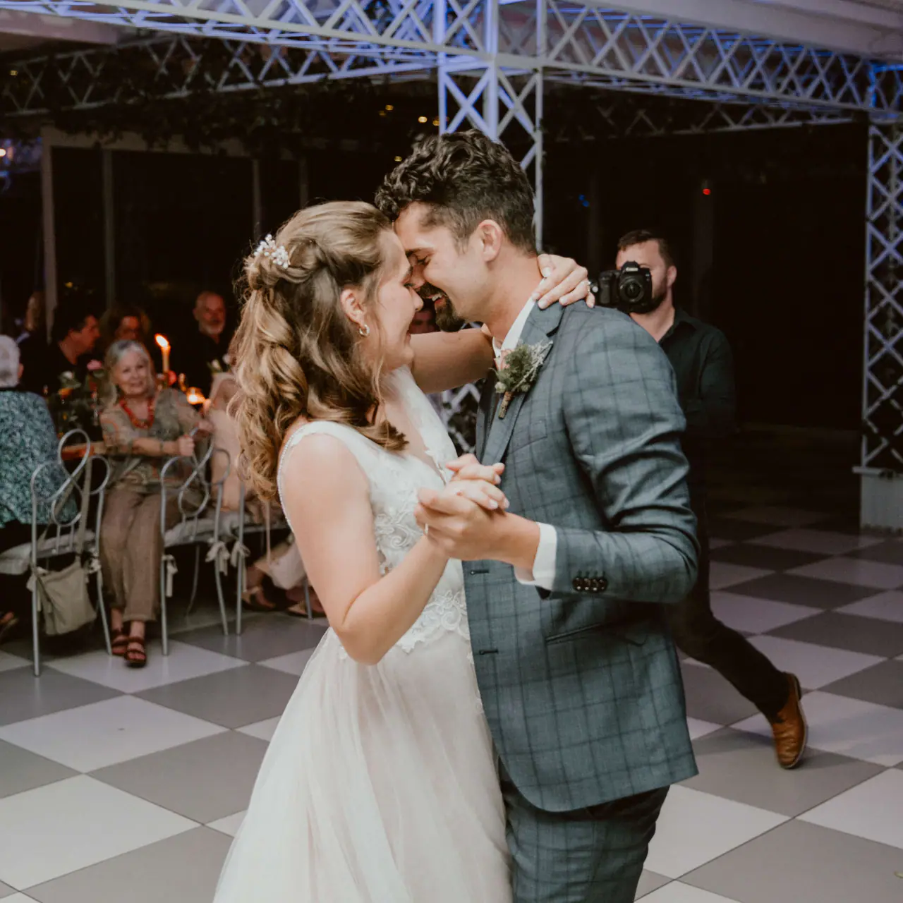 Karel and Madison laughing forehead to forehead during their first dance on the chequered floor at Belair Pavilion, Paarl