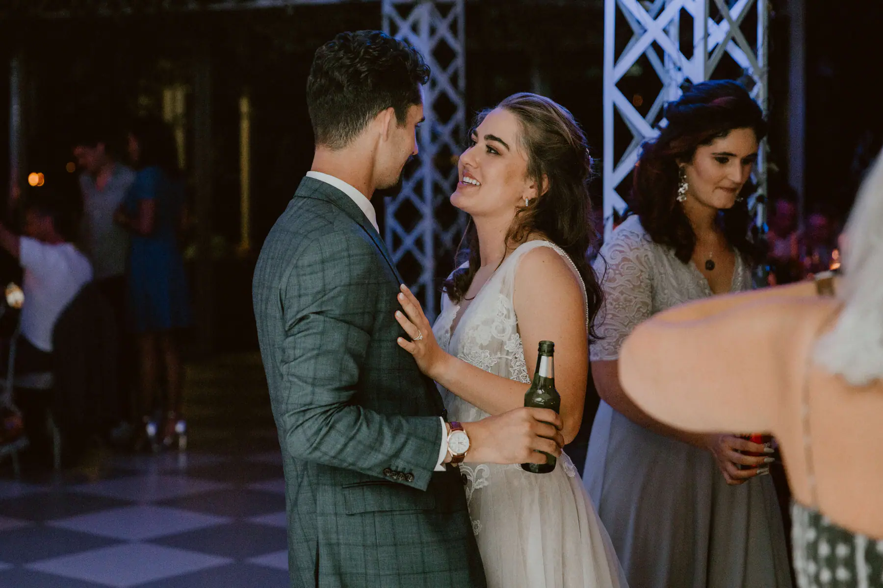 Karel in a blue checked suit, beer in hand, as Madison smiles up at him with her hand on his chest