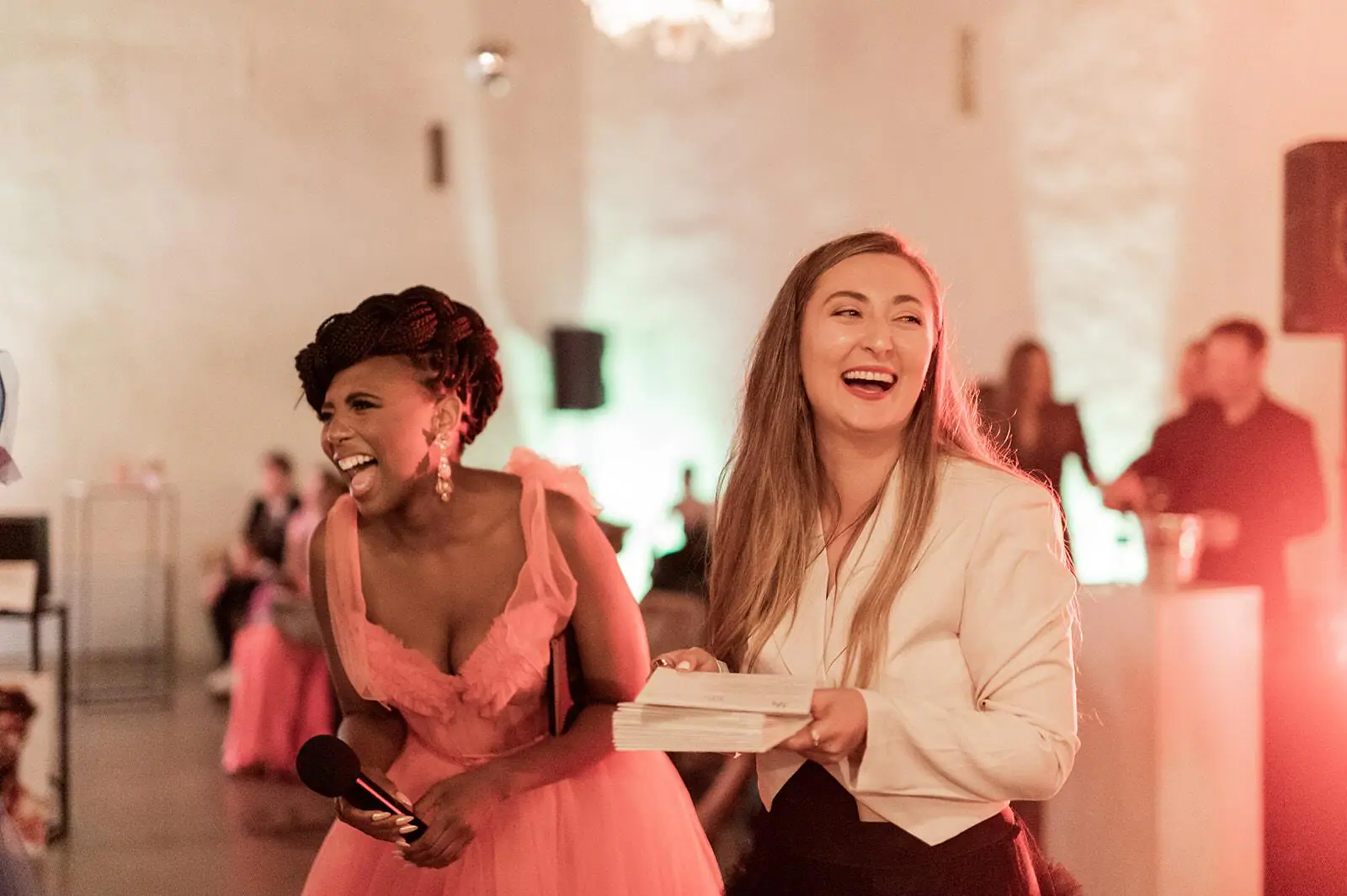 Host in a pink tulle gown and a woman in a cream blazer laughing together at the Bubbles & Bliss fundraiser for StellCare