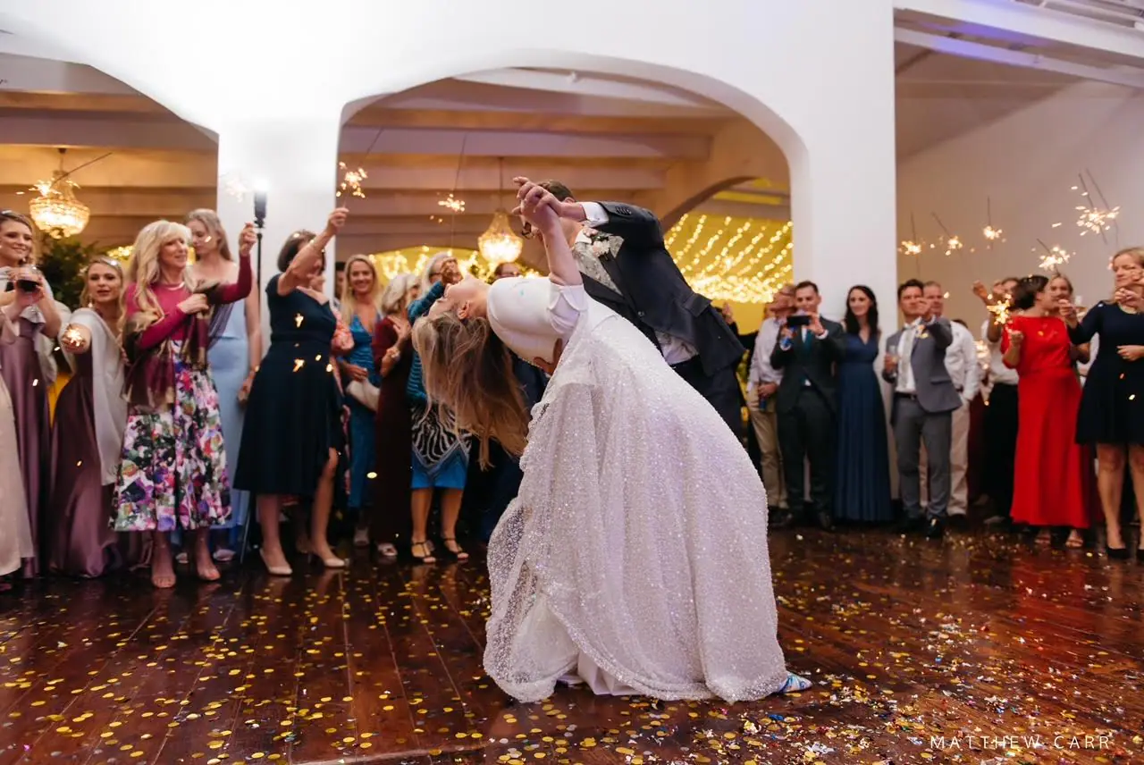 Nick dipping Camilla in her sequinned gown on a confetti-covered dance floor as guests wave sparklers at Zorgvliet Wines