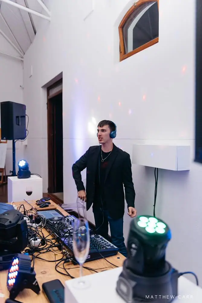 The DJ Company's DJ in blue headphones calling out from the decks at Zorgvliet Wines, moving head lights around him