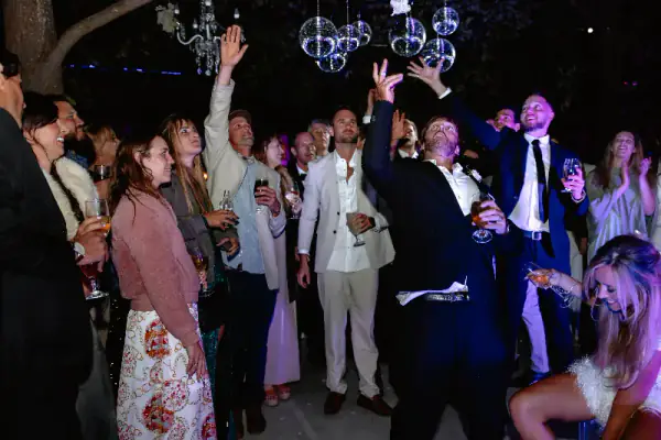 Groomsmen and guests with their hands in the air under disco balls