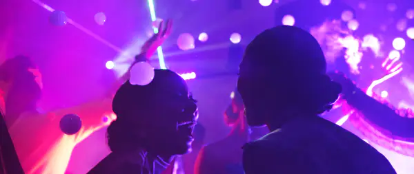 Guests dancing in purple light as a smoke bubble machine fills the air with bubbles