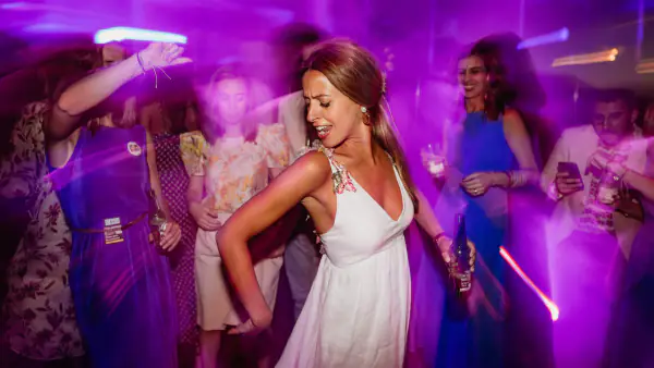 Bride dancing among her guests under The DJ Company's purple and pink party lighting