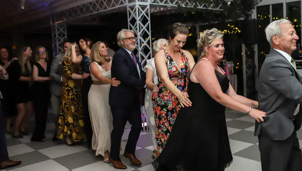 Wedding guests dancing in a conga line on a checkered dance floor in Stellenbosch