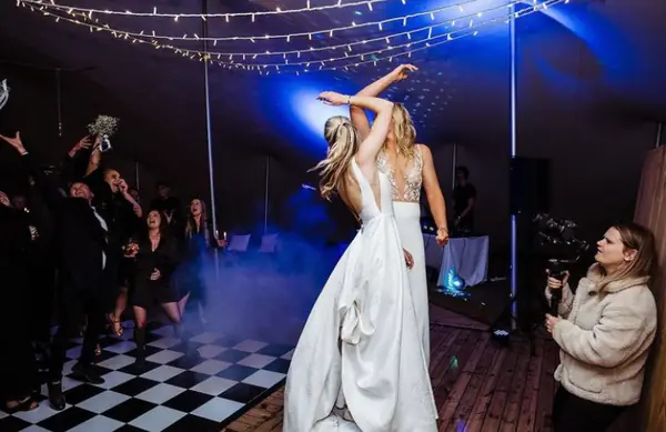 Bride dancing on a black and white checkered dance floor in blue light and low fog