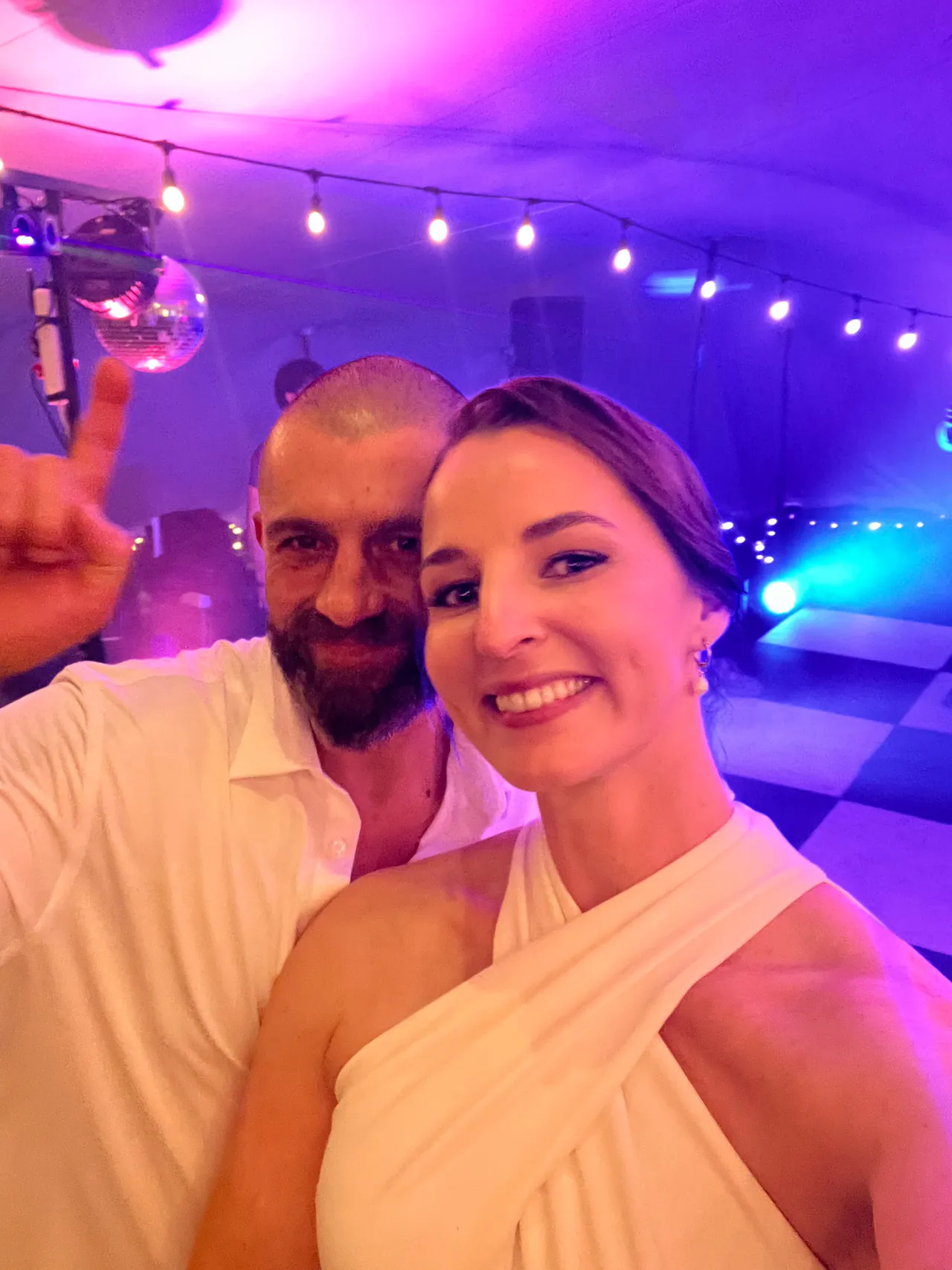 The bride and groom smiling for a selfie under coloured dance floor lights